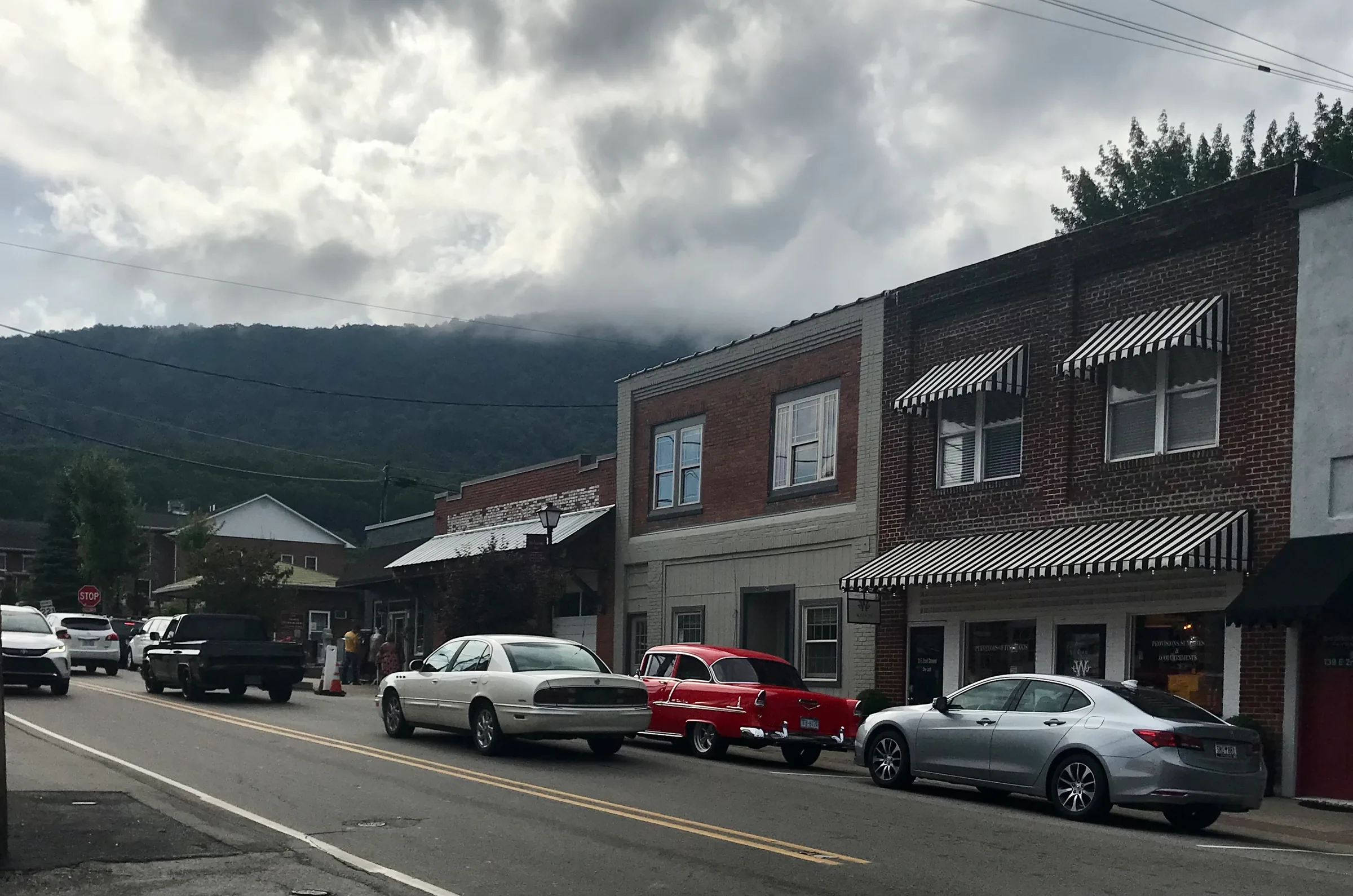 Awninged downtown storefronts and parked classic cars along US 221 Business in West Jefferson, NC.