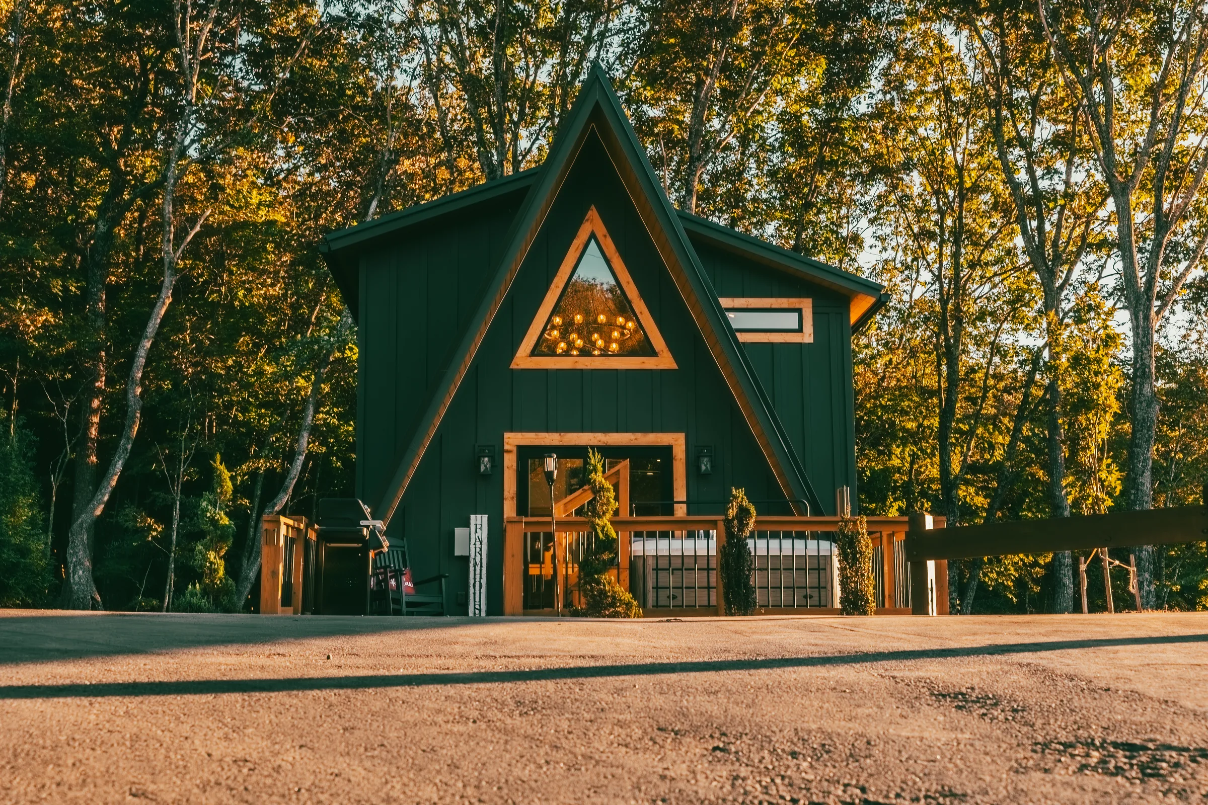 Front of the Farm A-frame cabin at golden hour among turning trees in West Jefferson, NC.