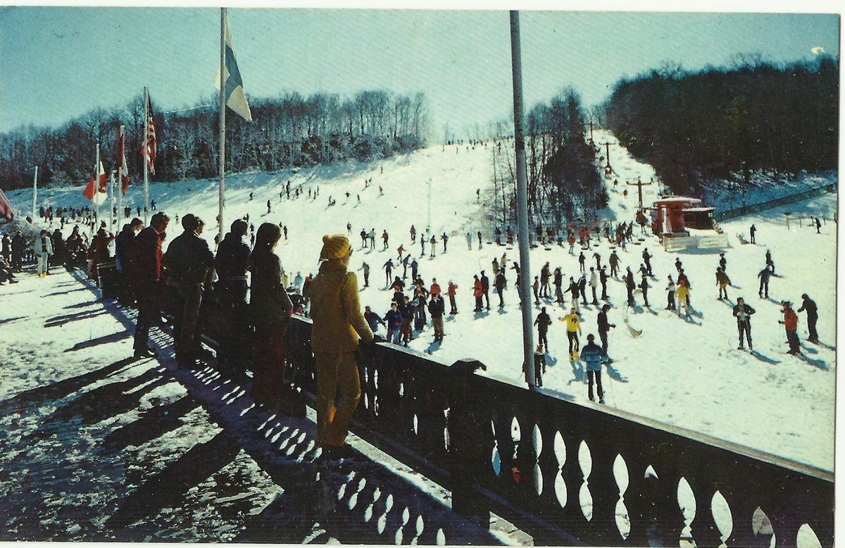 Vintage postcard of skiers crowding a sunny slope.