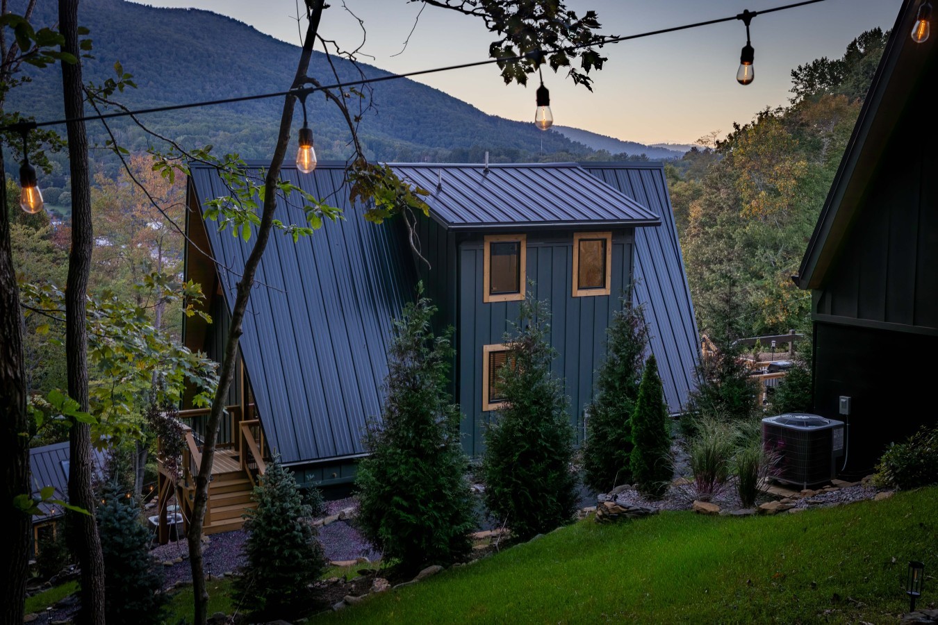 A-frame cabin with string lights and mountain backdrop