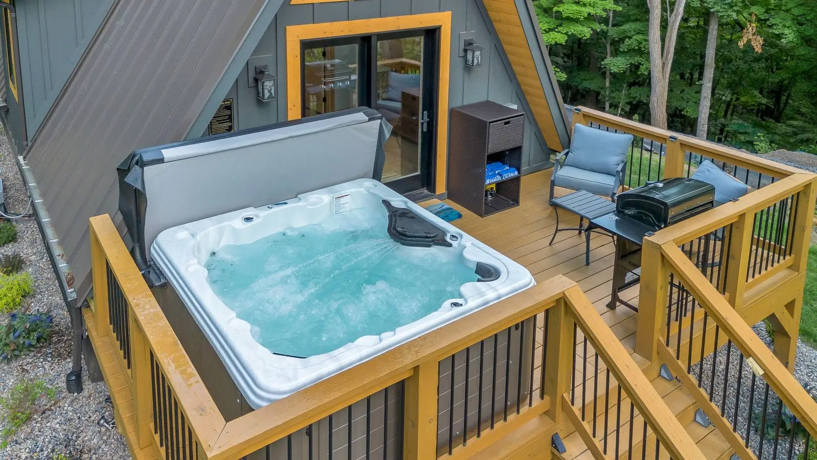 Bubbling XL deluxe hot tub on the High Peak deck with grill and lounge chairs