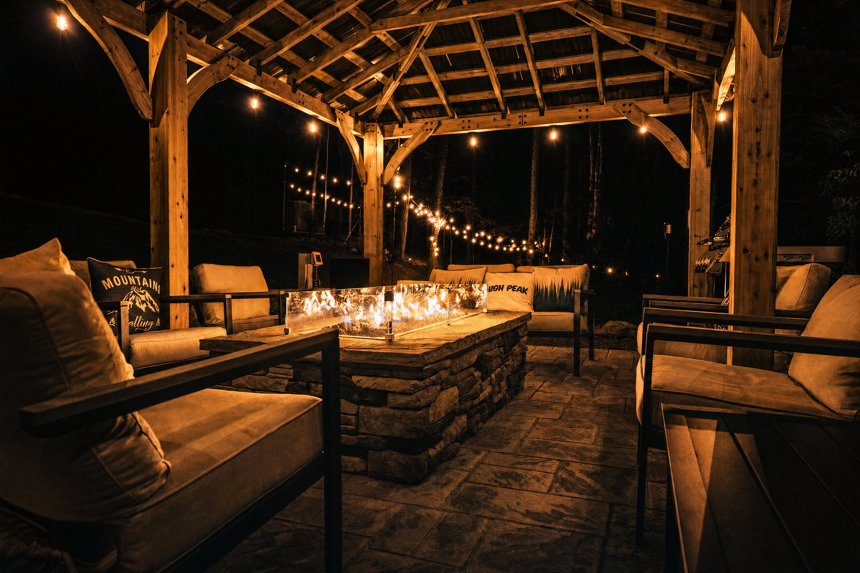 Gas-fueled stone fire pit and sofas under the timber pavilion at High Peak in West Jefferson, NC.