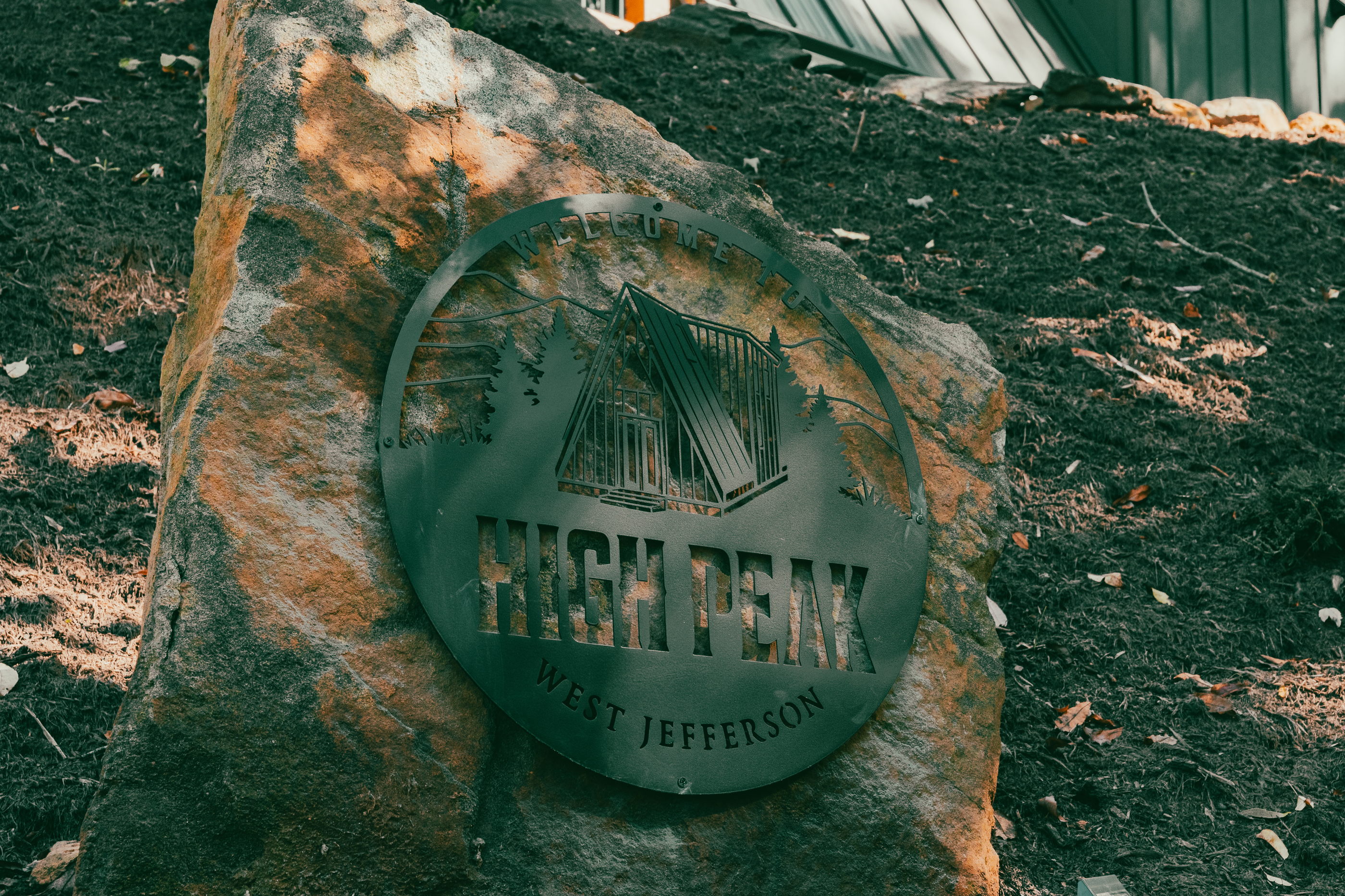 Stone sign reading High Peak West Jefferson on the cabin property in West Jefferson, NC.